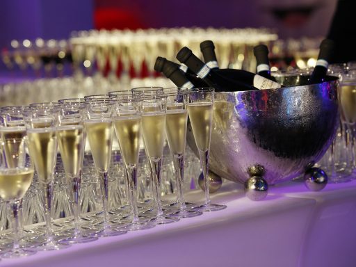 Bottles of Champagne in a cooler and glasses full of Champagne on a table with a white cloth