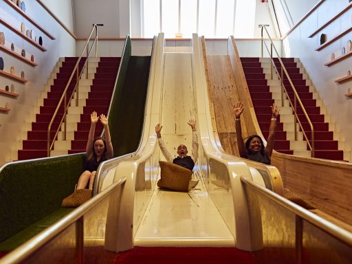 Three guests sliding down three different friction slides in the Wonderlab: The Equinor Gallery