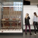 Two women listen to headphones as part of an exhibit in the Information Age gallery