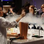 A bartender creating a cocktail with dry ice at our chemistry bar with event guests watching