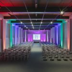 Event space with coloured lights and two aisles of chairs